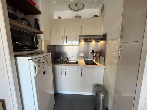 une petite cuisine avec des armoires blanches et un évier dans l'établissement Appartement proche plage, animaux admis, parking privatif - FR-1-324A-70, à Saint-Hilaire-de-Riez