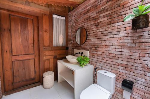 a bathroom with a white toilet and a brick wall at Nishiyama House Sambangan by The Lavana in Ambengan