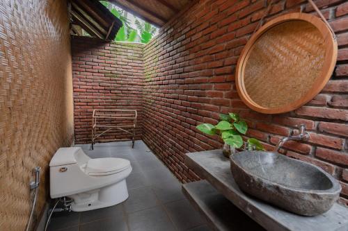 a brick bathroom with a toilet and a sink at Nishiyama House Sambangan by The Lavana in Ambengan