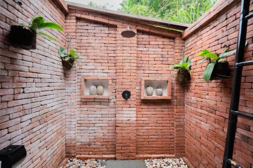 a brick wall with three windows with plants on it at Nishiyama House Sambangan by The Lavana in Ambengan