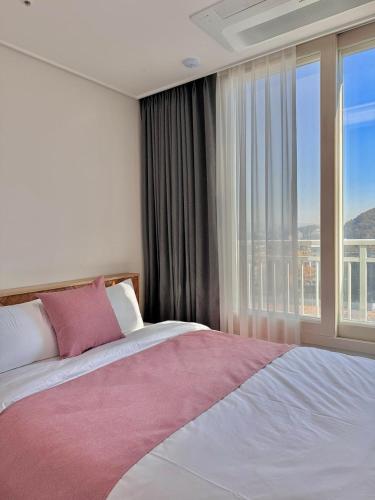 a bedroom with a bed and a large window at Eunhasu D&M Residence in Daejeon