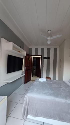 a bedroom with a bed and a flat screen tv at Suítes Canto do Pontal in Paraty