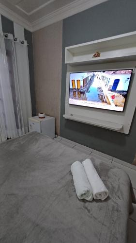 a bedroom with a bed and a tv on the wall at Suítes Canto do Pontal in Paraty