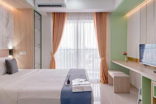 una camera d'albergo con un letto e una grande finestra di Homey and Comfort Stay Studio Apartment at Anwa Residence By Travelio a Tangerang