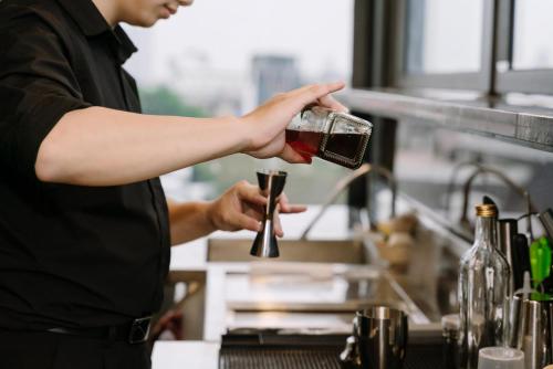 a man pouring wine into a glass in a kitchen at HOTEL de LAGOM in Hanoi