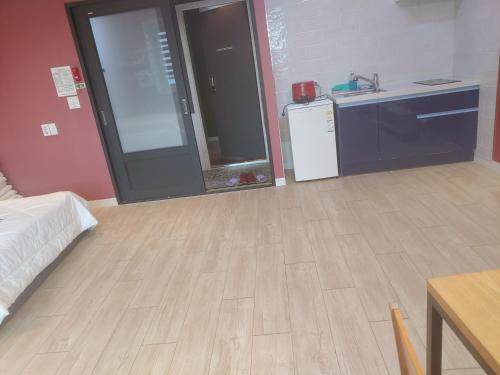 a room with a kitchen with a wooden floor at T stay guesthouse in Cheongju