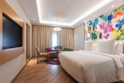 a hotel room with a large bed and a tv at Hotel Royal Orchid Bangalore in Bengaluru