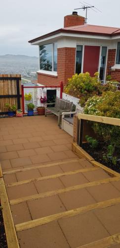 a patio with two benches in front of a house at Rosemount B&B by the Sea St Clair in Dunedin