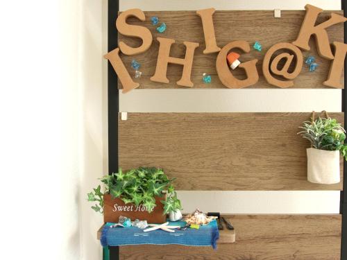 a shelf with plants and a sign that reads sit here at 赤瓦のちいさなお家 in Tunugusuku