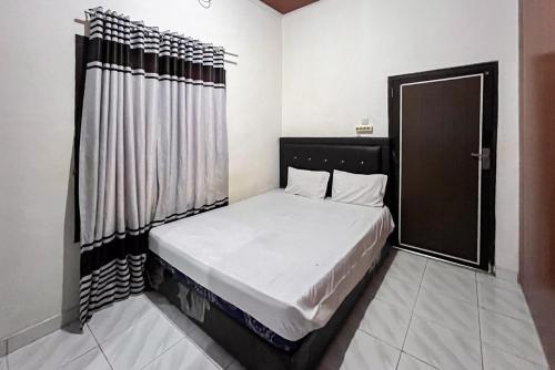a small bedroom with a bed with a black headboard at Kostel 99 Pangkal Pinang RedPartner in Pangkalpinang