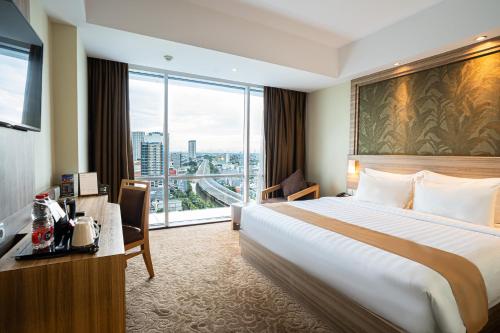 a hotel room with a bed and a desk and window at Hotel Horison Ultima Bekasi in Bekasi