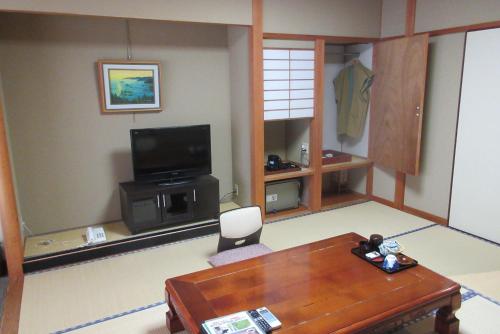 a living room with a table and a television at Asagiriso in Toyooka