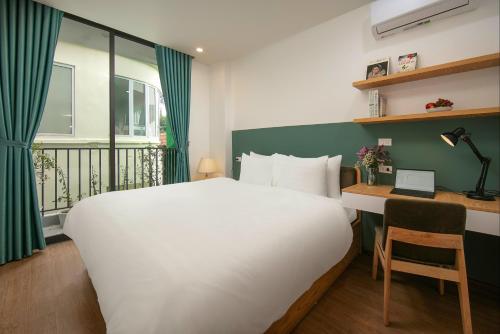 a bedroom with a bed and a desk with a laptop at Westlake Pearl Apartment - Hotel & Pearl Spa in Hanoi