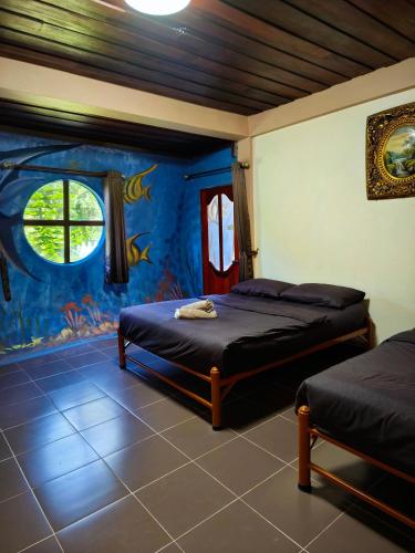a bedroom with two beds and a fish mural at Boat and House Resort Khao Kho in Khao Kho
