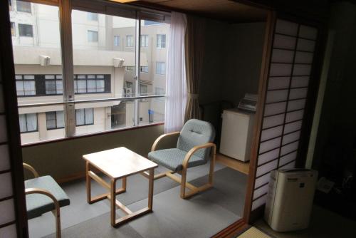 a room with a chair and a table and a window at Asagiriso in Toyooka