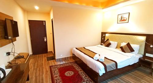 a bedroom with a large bed and a television at Garden Retreat Hotel in Gangtok