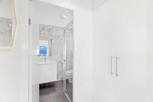 a white bathroom with a shower and a toilet at Bayside 6, 21 Victoria Pde - sensational water views, linen in Nelson Bay