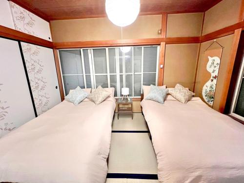 two beds in a room with a window at 千住4丁目2階 日本の和のお部屋スカイツリー9分秋葉原10分浅草12分 in Tokyo