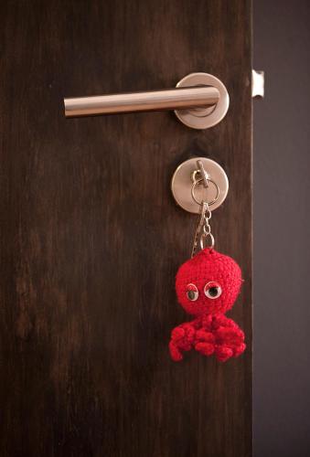 a red teddy bear keychain hanging on a door at Hostal Totsompops in Colera