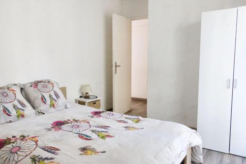une chambre blanche avec un lit avec un couvre-lit fleuri dans l'établissement Appartement spacieux à Perpignan, à Perpignan