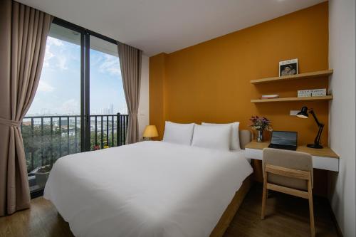 a bedroom with a white bed and a desk with a window at Westlake Pearl Apartment - Hotel & Pearl Spa in Hanoi