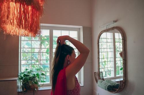 a woman is standing in front of a mirror at Utopia Varkala - Boutique stay in Odayam rice fields in Varkala