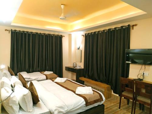 a hotel room with two beds and a television at Garden Retreat Hotel in Gangtok