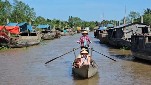 two people riding in a boat on a river at Út Bình Homestay in Vĩnh Long