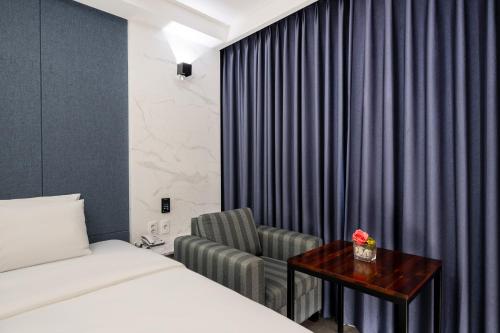 a hotel room with a bed and a chair at Hotel Artheim in Gwangju