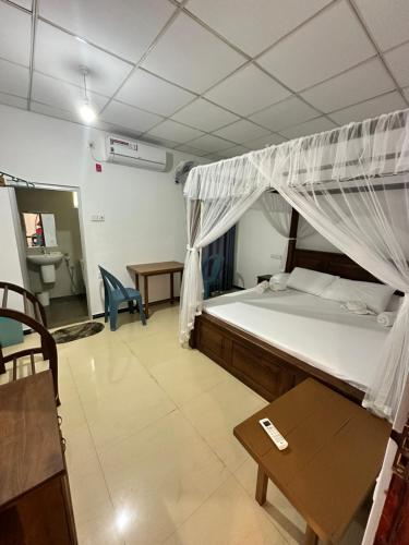 a bedroom with a bed and a desk and a table at Leafy Madiha in Matara