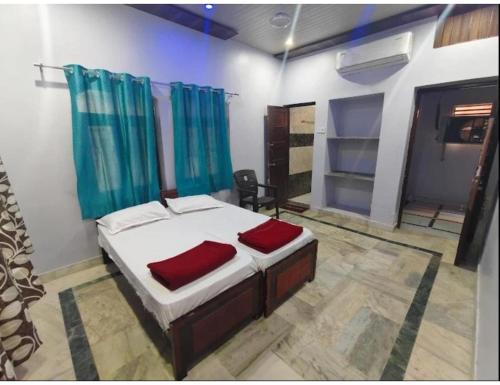 Un dormitorio con una cama con dos almohadas rojas. en Vaishnavi Shakti Peeth, Vrindavan, en Vrindāvan