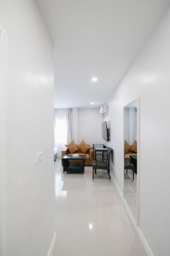 a white living room with a couch and a table at Eng Fah Luang Hotel in Ban Huai Phlu