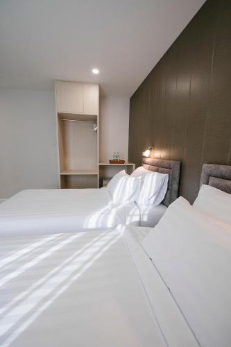 two beds in a hotel room with white sheets at Eng Fah Luang Hotel in Ban Huai Phlu