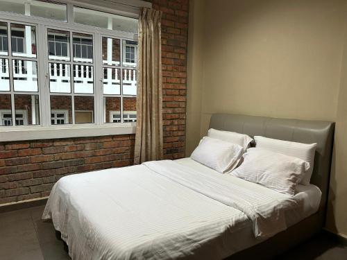 a bed with white sheets and pillows in front of a window at Kundasang Guesthouse in Kundasang