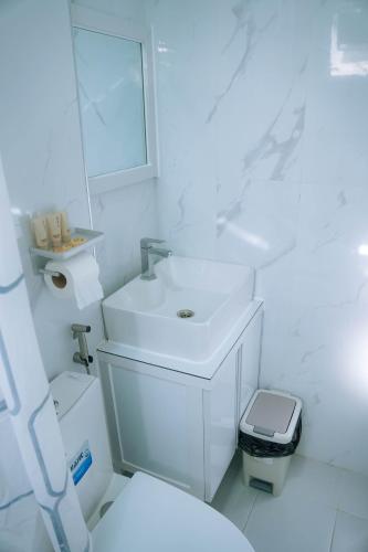 a white bathroom with a sink and a toilet at La Casa 1101 in Amoloñgin