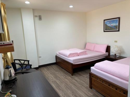 two beds in a room with pink sheets at 今友緣二館民宿 in Dongyin