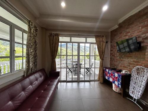 a living room with a couch and a large window at Kundasang Guesthouse in Kundasang