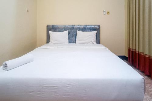 a large bed with white sheets and pillows at RedDoorz at Senaz Guesthouse Mataram in Mataram