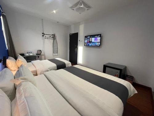 a room with three beds and a tv on the wall at Asia Premium Hotel Kuala Terengganu in Kuala Terengganu