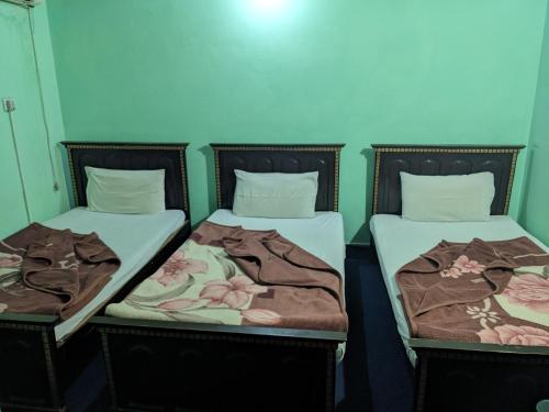 Dos camas una al lado de la otra en una habitación. en New Grace Hotel, en Islamabad