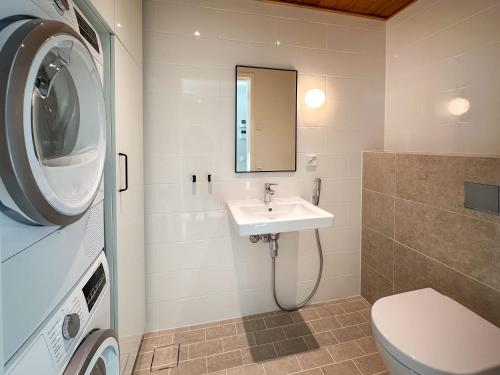 a bathroom with a sink and a washing machine at Westwind Suite in Kuningatarranta Hanko in Hanko