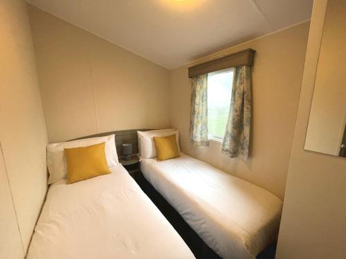 two beds in a small room with a window at Pass the Keys Cosy Welcoming 3BR in Beautiful Country Park in Beattock