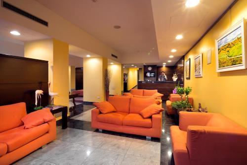 a lobby with orange couches and chairs in a room at Hotel Il Viandante in Terranuova Bracciolini