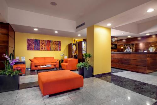 an office lobby with an orange couch and a bar at Hotel Il Viandante in Terranuova Bracciolini