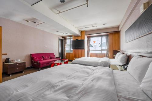 a hotel room with two beds and a red couch at CHECK inn Express Taichung Fengchia in Taichung
