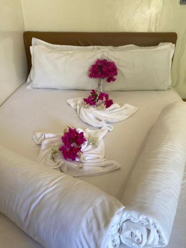a white bed with flowers in towels on it at Maavaharu Guest House Himmafushi in Himmafushi