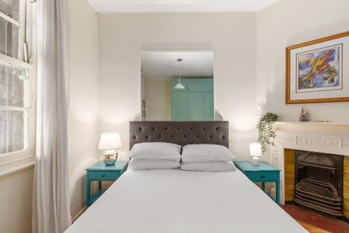 a bedroom with a large bed with two blue tables at Quaint 3-Bed Heritage Home in the Heart of Sydney in Sydney