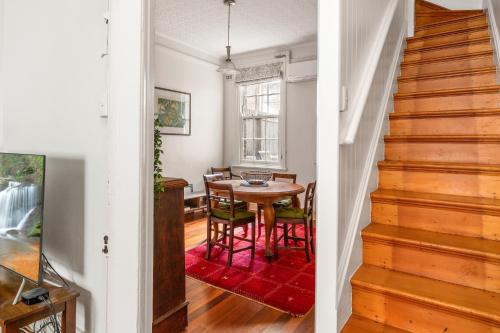 a dining room with a table and chairs and a staircase at Quaint 3-Bed Heritage Home in the Heart of Sydney in Sydney