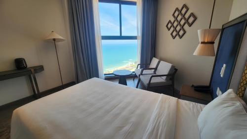 a hotel room with a large white bed and a window at Apec Mandala Mũi Né Resorts & Hotels NN in Phan Thiet