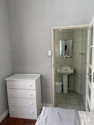 a white bathroom with a sink and a mirror at Bennyz Guest House in Pretoria